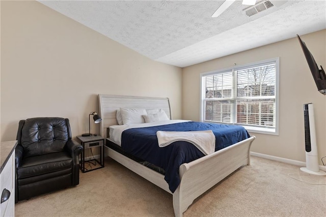 bedroom featuring ceiling fan, light colored carpet, and a textured ceiling