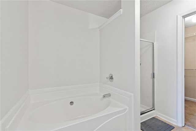 bathroom with tile patterned flooring, plus walk in shower, and a textured ceiling