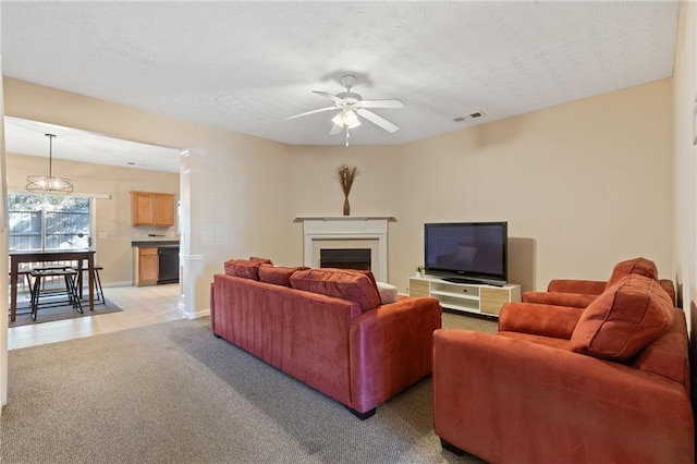 living room featuring ceiling fan, carpet floors, and a textured ceiling