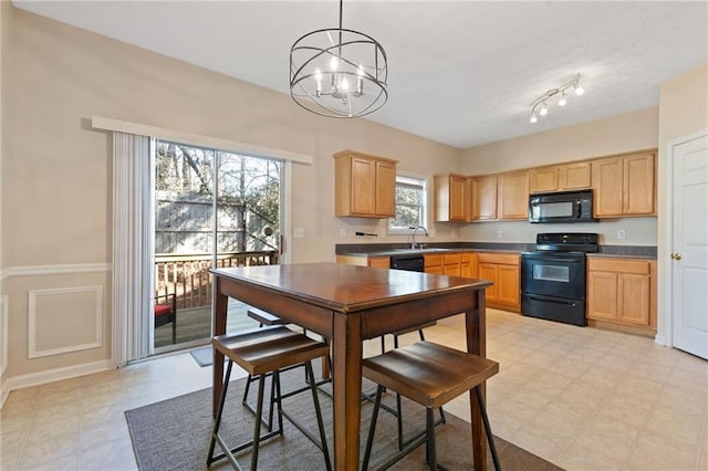 kitchen with hanging light fixtures, a healthy amount of sunlight, light brown cabinetry, and black appliances