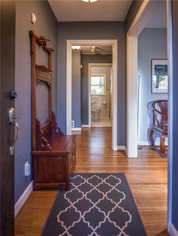 hall with baseboards and wood finished floors