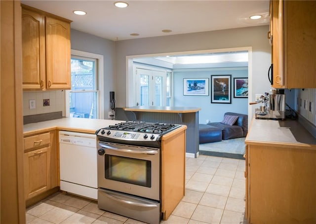 kitchen with light countertops, white dishwasher, stainless steel range with gas cooktop, and a peninsula