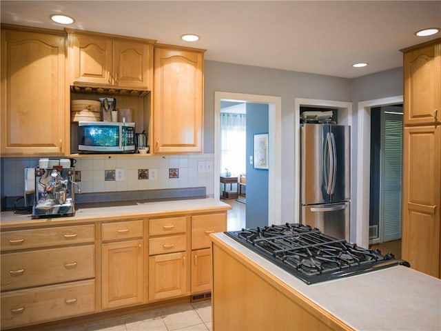 kitchen with light tile patterned floors, tasteful backsplash, recessed lighting, light countertops, and appliances with stainless steel finishes