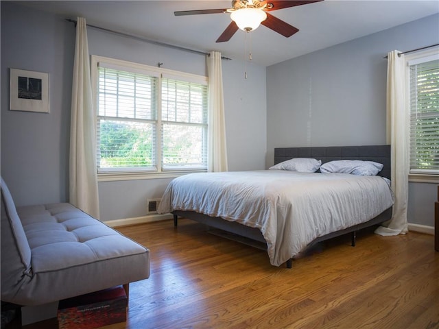 bedroom with baseboards, visible vents, ceiling fan, and wood finished floors