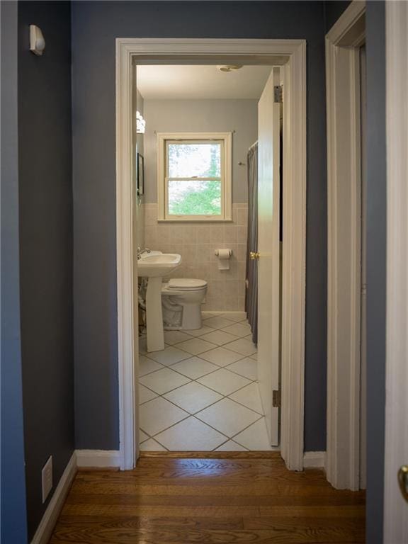 full bathroom with tile walls, wainscoting, toilet, wood finished floors, and a sink