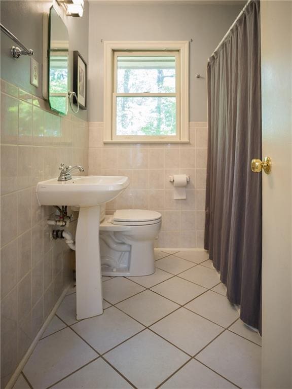 bathroom with wainscoting, tile patterned flooring, toilet, and tile walls