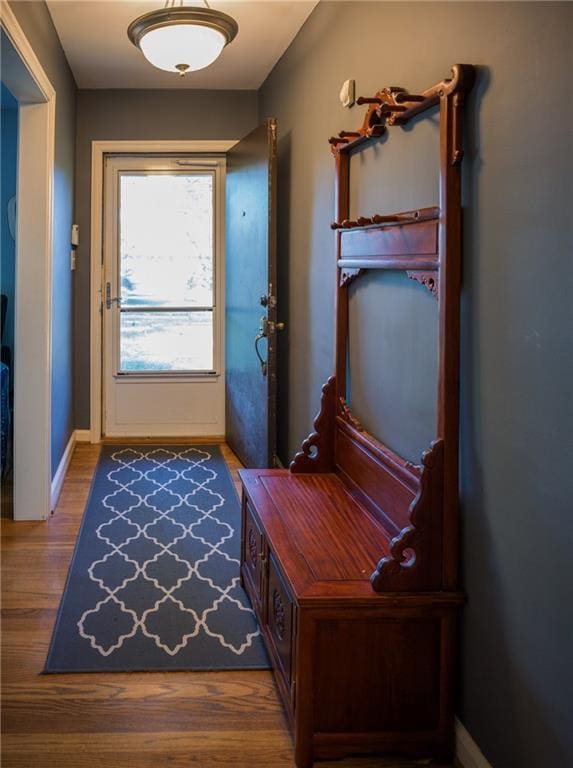 doorway with baseboards and wood finished floors