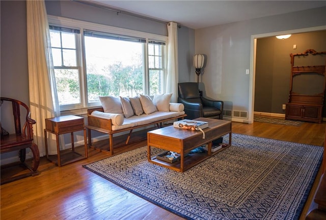 living room with visible vents, baseboards, and wood finished floors