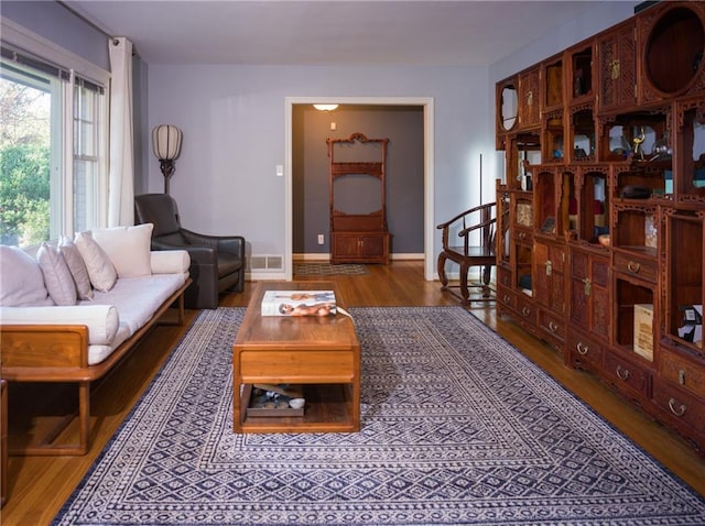 living room featuring wood finished floors, visible vents, and baseboards