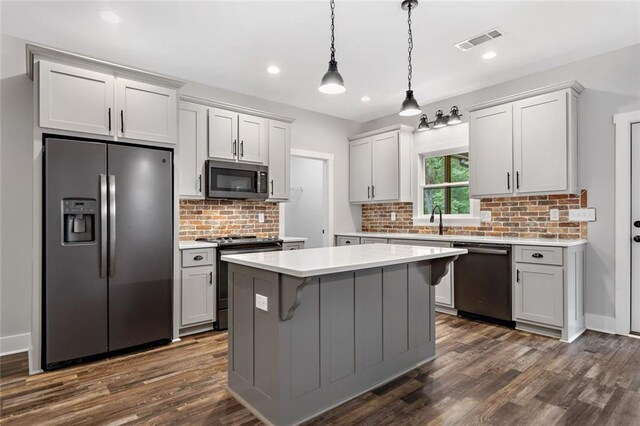 kitchen with stainless steel appliances, light countertops, a kitchen island, dark wood-type flooring, and recessed lighting