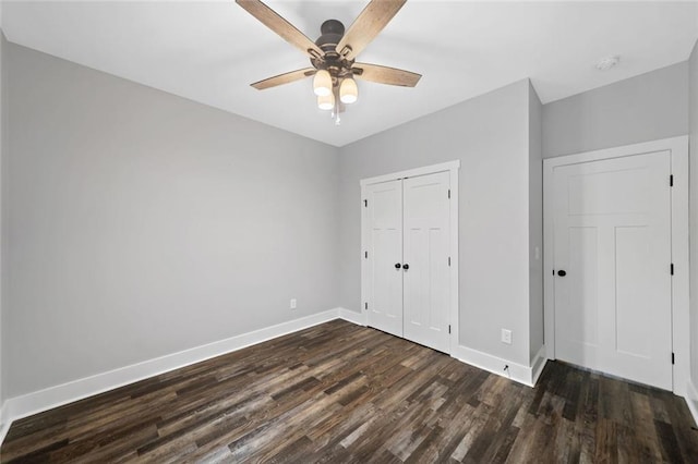unfurnished bedroom with dark wood-type flooring, baseboards, a closet, and a ceiling fan