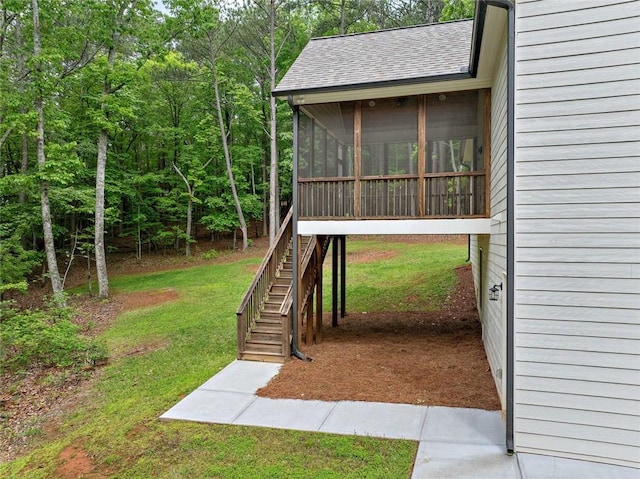 view of grassy yard featuring a sunroom and stairway