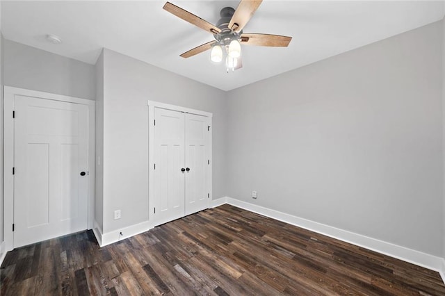 unfurnished bedroom featuring baseboards, dark wood-style floors, a closet, and ceiling fan