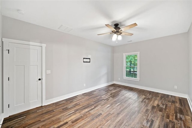 spare room with dark wood-style floors, a ceiling fan, and baseboards