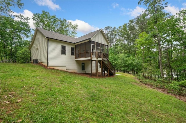 back of property with a sunroom, central air condition unit, stairway, and a yard