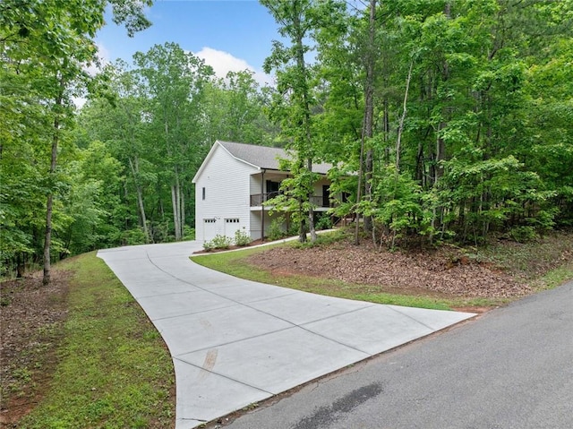 view of side of property featuring an attached garage, driveway, and a forest view