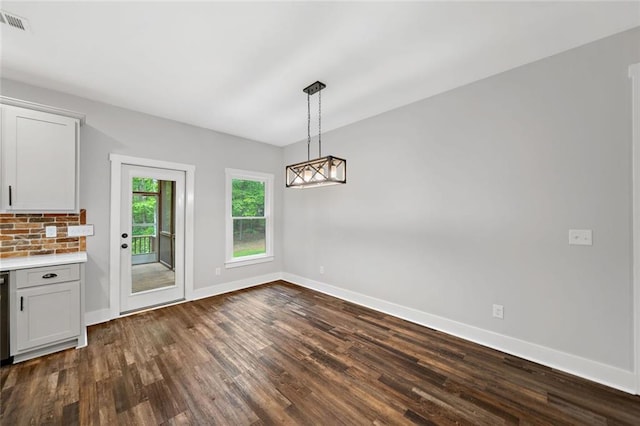 unfurnished dining area featuring dark wood-style floors, baseboards, and a chandelier