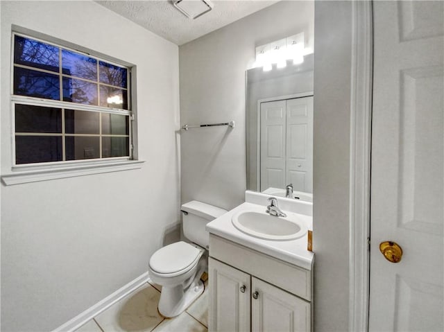 bathroom with toilet, a textured ceiling, tile patterned floors, and vanity