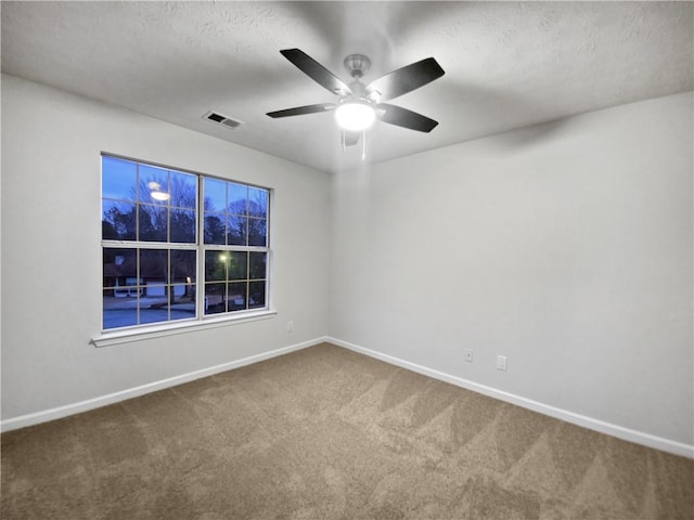 carpeted spare room featuring ceiling fan and a textured ceiling