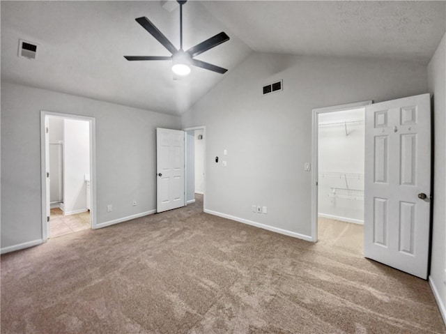 unfurnished bedroom with vaulted ceiling, ensuite bathroom, a closet, a walk in closet, and ceiling fan