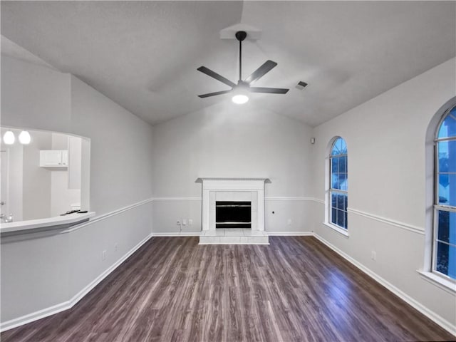 unfurnished living room featuring lofted ceiling, wood-type flooring, a tile fireplace, and ceiling fan