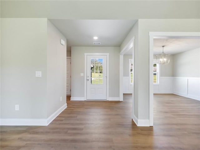 entryway featuring baseboards, wood finished floors, visible vents, and a notable chandelier