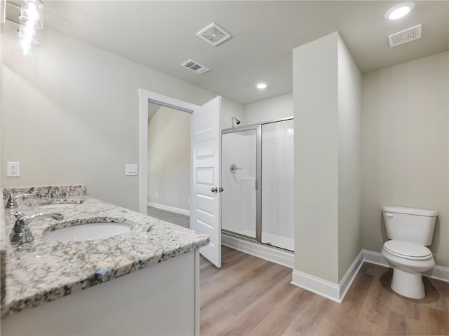 bathroom with toilet, a stall shower, visible vents, and wood finished floors