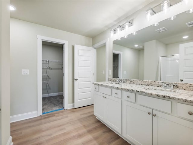 bathroom featuring visible vents, a sink, baseboards, and wood finished floors