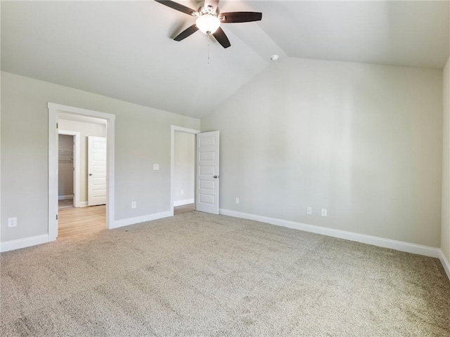 empty room featuring light carpet, vaulted ceiling, baseboards, and ceiling fan