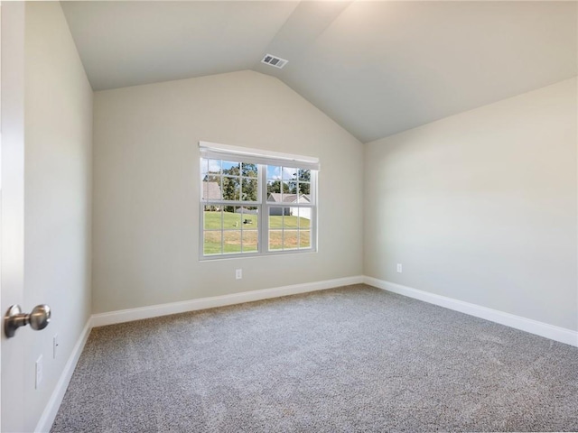 spare room featuring carpet floors, visible vents, vaulted ceiling, and baseboards