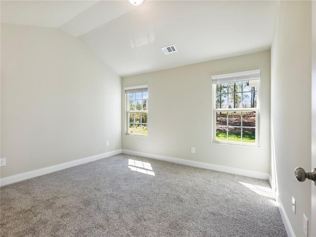 empty room featuring carpet floors, lofted ceiling, visible vents, and baseboards