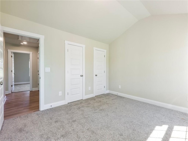 unfurnished bedroom featuring attic access, lofted ceiling, carpet flooring, and baseboards