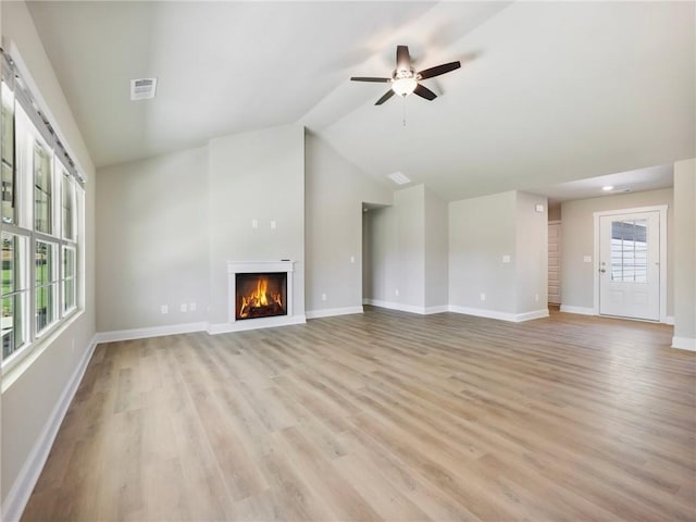 unfurnished living room featuring light wood-style flooring, visible vents, baseboards, vaulted ceiling, and a lit fireplace