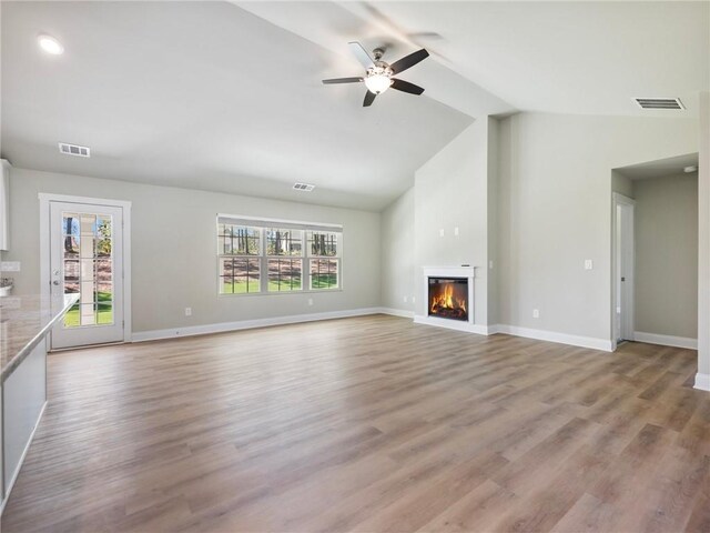 unfurnished living room featuring light wood-type flooring, visible vents, and a glass covered fireplace