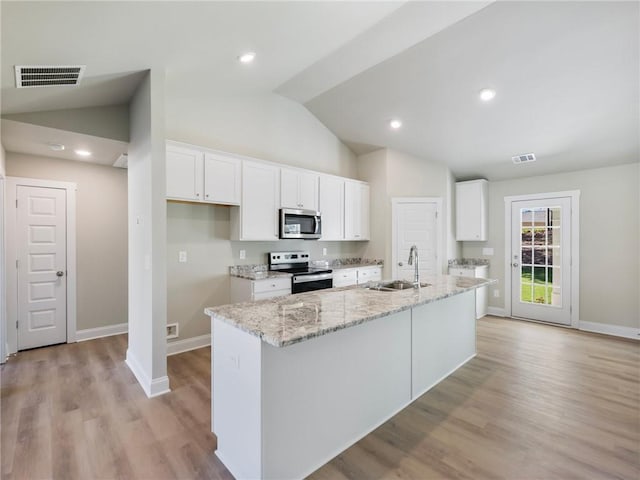 kitchen with lofted ceiling, white cabinetry, stainless steel appliances, and a sink