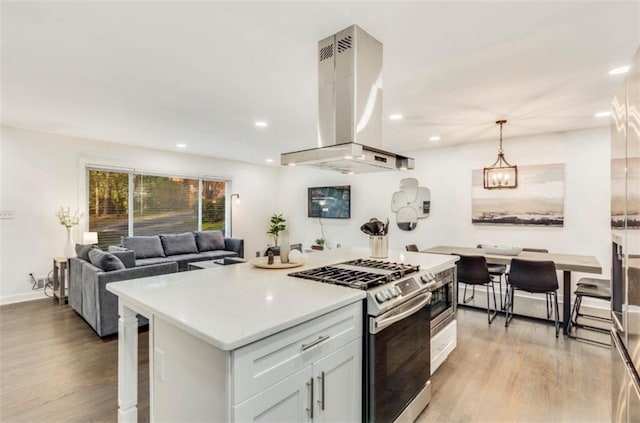 kitchen with a center island, white cabinets, island exhaust hood, decorative light fixtures, and stainless steel range with gas cooktop