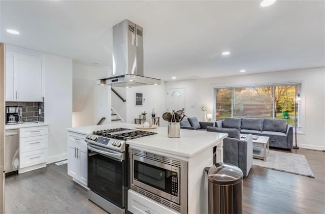 kitchen with island exhaust hood, appliances with stainless steel finishes, decorative backsplash, and white cabinets