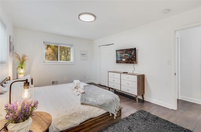 bedroom with dark hardwood / wood-style flooring and a closet