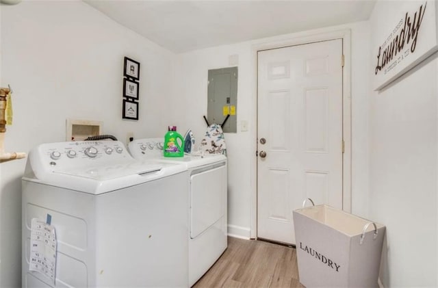 clothes washing area with washing machine and dryer, electric panel, and light wood-type flooring