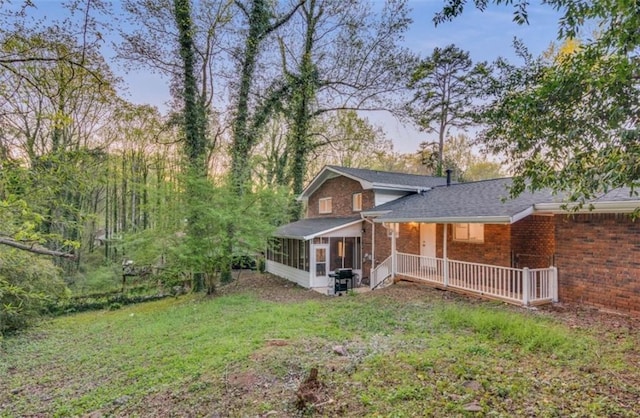 back of property featuring a yard and a sunroom