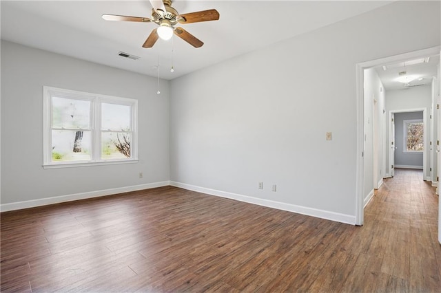 unfurnished room featuring visible vents, baseboards, attic access, and wood finished floors