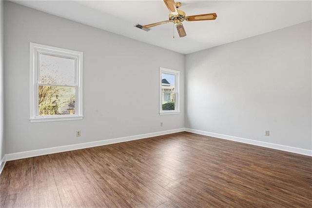 empty room with dark wood-style floors, a healthy amount of sunlight, and baseboards