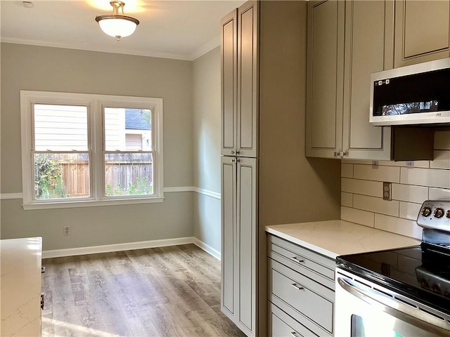 kitchen featuring ornamental molding, light stone counters, decorative backsplash, light wood-style flooring, and stainless steel appliances