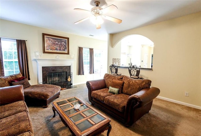 living room featuring a fireplace, light colored carpet, and ceiling fan