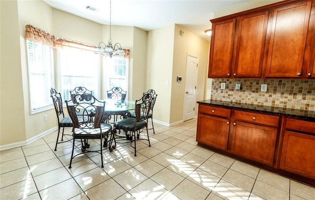 kitchen with decorative light fixtures, light tile patterned flooring, tasteful backsplash, and dark stone countertops