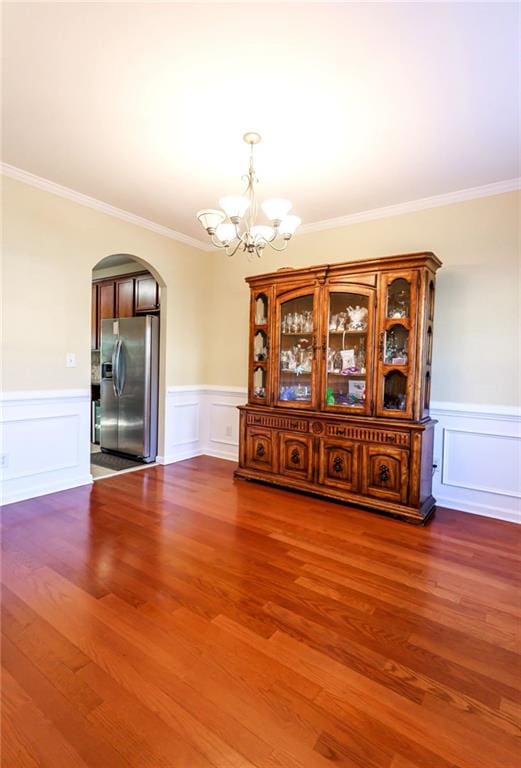 unfurnished dining area with wood-type flooring, a notable chandelier, and crown molding