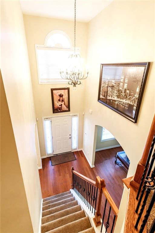 entryway with wood-type flooring, a towering ceiling, and a notable chandelier