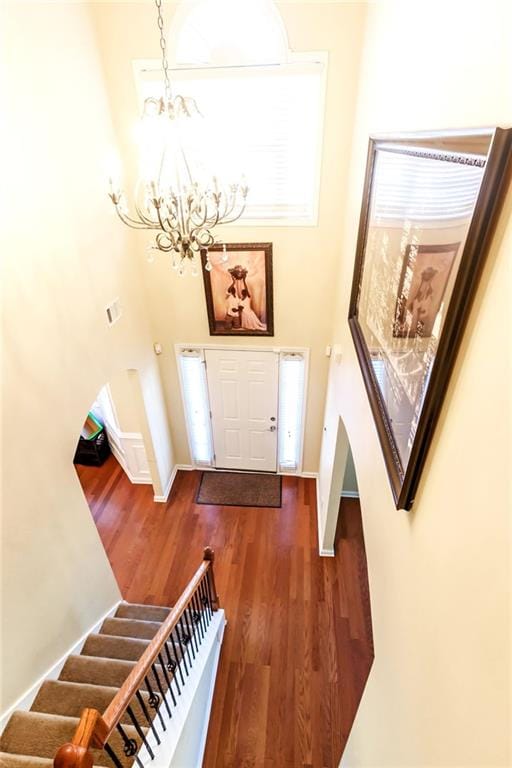 entryway with a towering ceiling, a chandelier, and dark hardwood / wood-style flooring