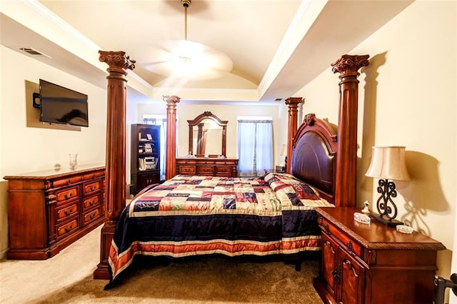 carpeted bedroom with ceiling fan, a tray ceiling, ornamental molding, and decorative columns