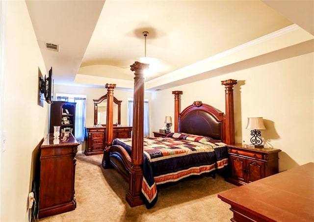 bedroom with light colored carpet, a raised ceiling, and ornate columns